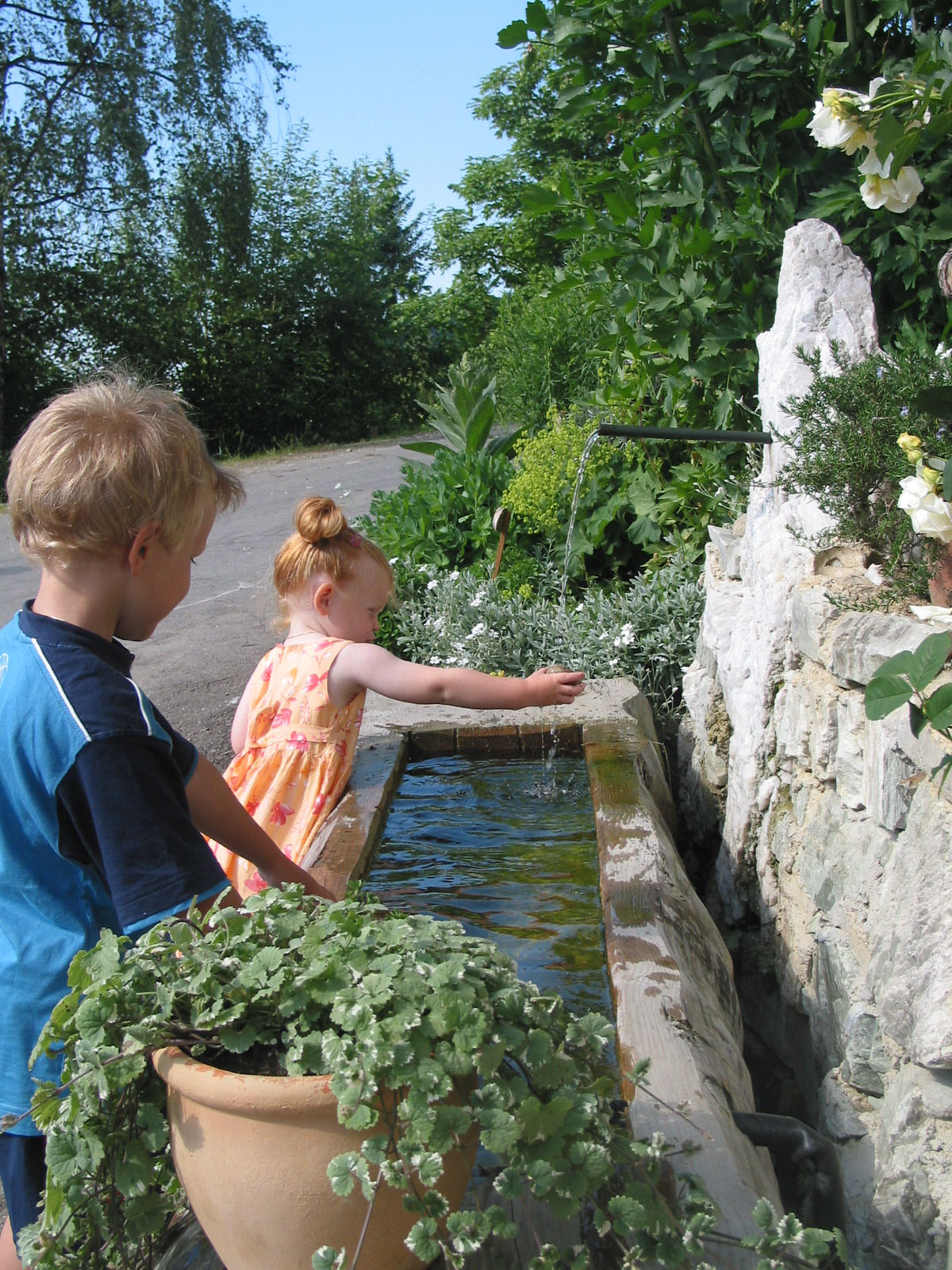 Kinder spielen mit Wasser vorm Brunnen bei Urlaub am Bauernhof Grabenhofer
